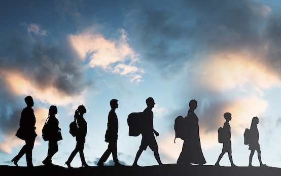 silhouette of young and adult immigrants with a blue sky in its background
