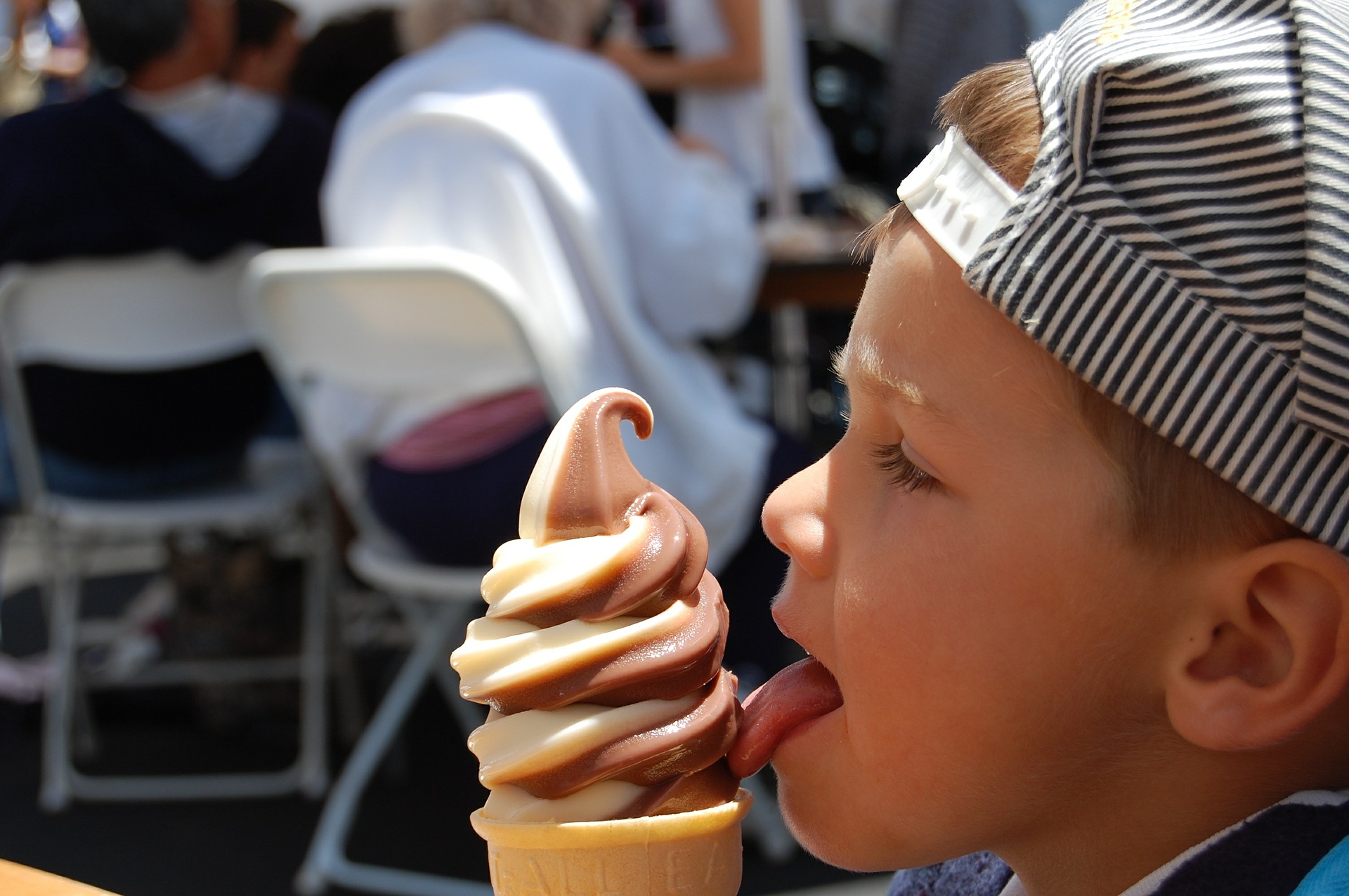 Boy with stripes cap licked the ice cream
